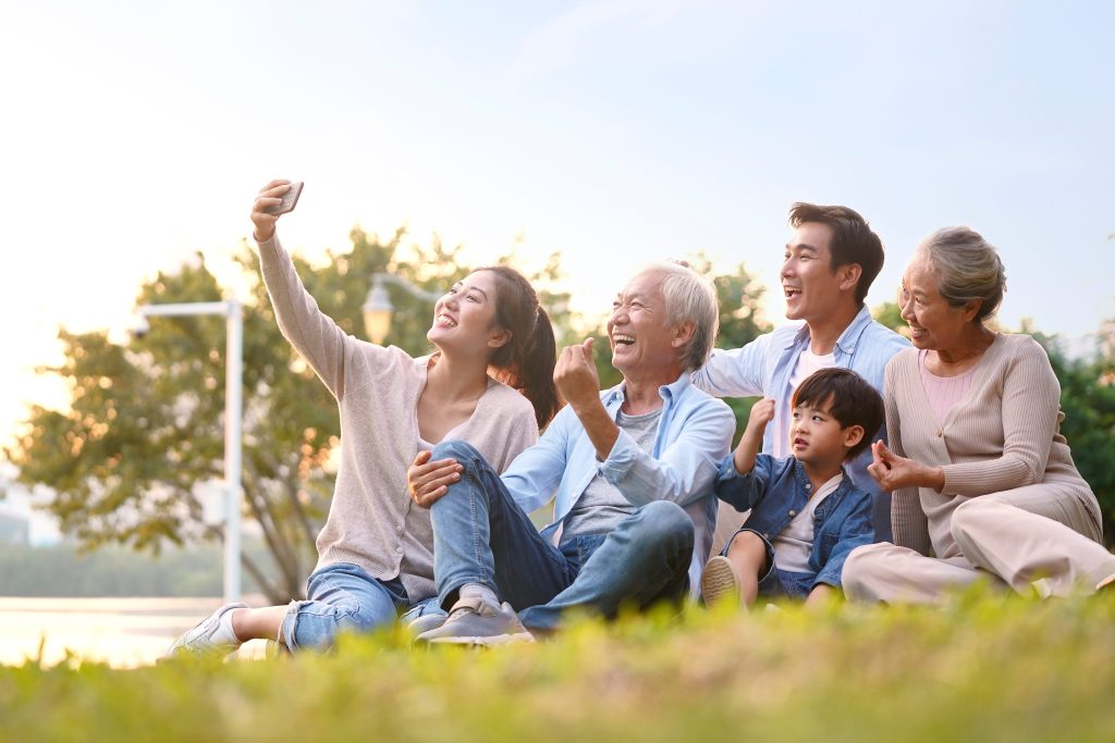 Three,Generation,Happy,Asian,Family,Sitting,On,Grass,Taking,A